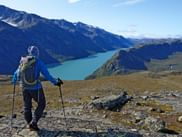 Hiker enjoys the view of large mountain lake and mountains in Jotunheimen National Park