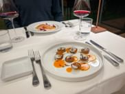 Weißer Teller mit Süßkartoffel-Canapés mit Creme, serviert mit Rotwein auf weißer Tischdecke in der Toskana.