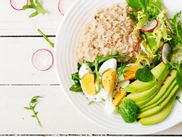 Plate with eggs, avocado, salad, radishes and cooked oatmeal