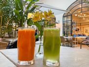 Fresh carrot juice and green juice on a table decorated with flowers