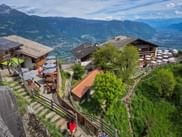 Alpine Gästehäuser am Hochmuth mit traditionellen Gebäuden, Außenterrassen und Panoramablick auf grüne Bergtäler.