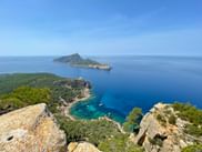 Blick von Felsen bei Sant Elm auf Mallorcas GR221, mit türkisfarbener Bucht, grüner Halbinsel und Insel im blauen Mittelmeer.