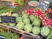 Frisches Gemüse wie Artischocken und Radieschen bei einem Marktstand