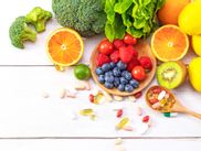 Verschiedene Obst und Gemüsesorten wie Kiwi, Orangen, Zitronen, Brokkoli, Salat, Heidelbeeren, Himbeeren, Tomaten und Nahrungsergänzungsmittel in Form von Kapseln