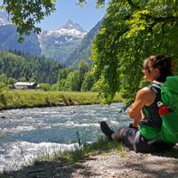 Hiker sitting by the stream with a view of the Loferer Steinberge mountains