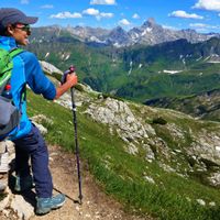 Wanderin auf dem Nebelhorn sitzt auf Bank mit Blick auf Berge