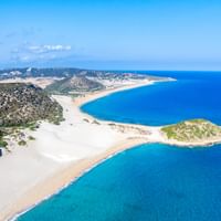 Aerial view of Golden Beach on Karpaz Peninsula, Cyprus, showing white sandy beaches, turquoise waters, and a small green island.