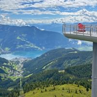 Erhöhte Aussichtsplattform auf der Schmittenhöhe mit Besuchern und Blick auf den Zeller See, grüne Berge und Täler in den Kitzbüheler Alpen.