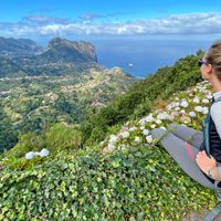 Hiker enjoys the view of the coastal landscape from the Miradouro da Portela viewpoint in Madeira
