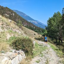 Hiker on a stony hiking trail under a blue sky