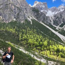 Hiker in front of a mountain view of the Dolomites with a blue sky