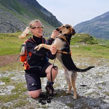 Hiker with dog in front of a mountain backdrop