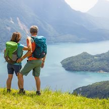 Hikers admire the beautiful Lake Molveno surrounded by mountains
