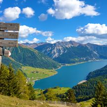 Hiking signpost with a view of Lake Reschen