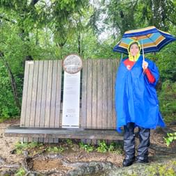 Hiker with rain gear in front of bench with umbrella