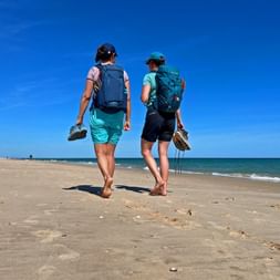 Hikers walk barefoot across the beach on Ilha de Tavira
