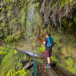 Hikers under the waterfall along the path