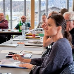 Business meeting at Eurofun Touristik Training Days 2026. Participants seated at conference table with documents and water bottles, mountains visible through windows.