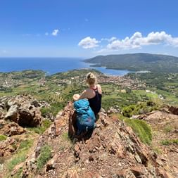 Hiking break on a rocky outcrop with a view of a village below and the coast