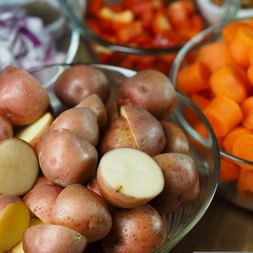 Halbierte Kartoffeln in einer Schüssel, Karottenstücke in einer Schüssel