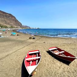 Beautiful sandy beach with fishing boats and calm waves