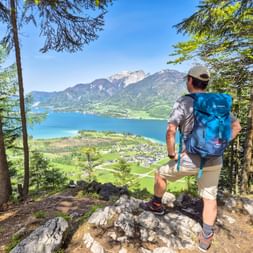 Hiker enjoys the panoramic view of the Wolfangsee and the Schafberg