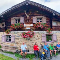 Mr Preusche with friends in front of a rustic mountain hut