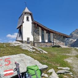 Rettenbach glacier memorial chapel with backpack and marker on stone