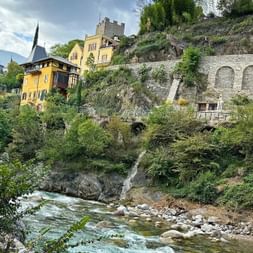 Fluss mit Häuserfronten am Ufer in Meran