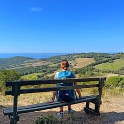 Hiker sitting on a bench with a hilly landscape in the background