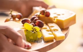 Various cheeses with grapes on a wooden board