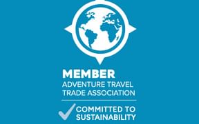 Blaues Abzeichen mit Globus und Kompass. Text: Member Adventure Travel Trade Association, Committed to Sustainability, Verified by ATTA.