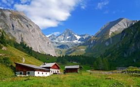 Blick über Almwiesen und Bergbauernhöfe auf den Großglockner