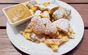 Plate of Kaiserschmarrn dusted with powdered sugar served with applesauce on a white plate at Angerlalm near Kitzbühel Griessbachklamm.