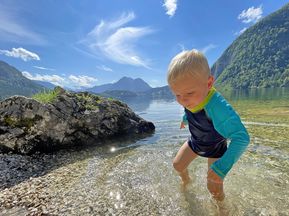 Kind im herrlich klaren Ausseersee während dem Familienwandern Salzkammergut Flüsse und Seen