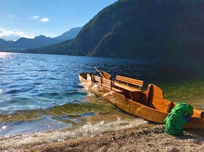 Wanderrucksack angelehnt an einem Boot am Ufer eines Sees