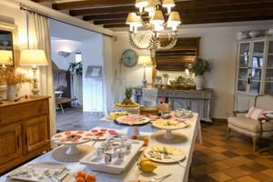 Frühstücksbuffet im Can Quatre Sóller mit Platten voller Aufschnitt, Käse und Obst in einem rustikalen Speiseraum mit Holzbalken.