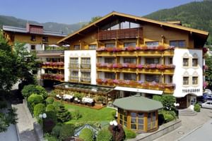 Hotel Tirolerhof exterior view with traditional Alpine architecture, flower-decorated balconies, and mountain backdrop in Zell am See.