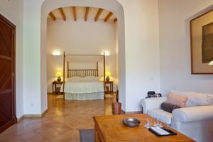 Geräumige Junior-Suite im Son Palou Orient mit Rundbogen, Holzbalken, Himmelbett, weißem Sofa und Terrakotta-Fliesenboden.