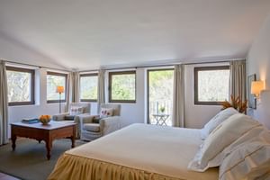 Helles Superior Doppelzimmer im Son Palou Orient mit weißem Bett, gestreiften Sesseln, Holztisch und fünf Fenstern mit Bergblick.