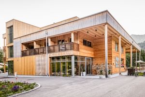 Modernes Holzhotel LechZeit Elmen mit Glasfassade, überdachter Terrasse und Bergkulisse in Österreich.