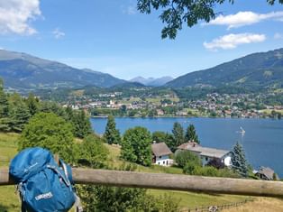 Blue Eurohike backpack resting on wooden fence overlooking alpine lake in Carinthia with mountains, villages and boats in scenic valley.