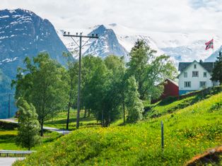 View of the Jostedalsbreen glacier with dandelion meadows and a typical white wooden house in the foreground