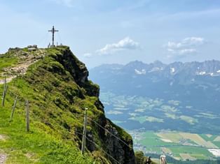 Blick auf den Wanderweg zum Gipfelkreuz, mit dem Tal und dem Wilden Kaiser im Hintergrund