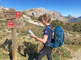 Wanderer am GR221 vor einem Wegweiser Richtung Cuber Stausee
