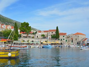 Ein Hafen mit den landestypischen Steinhäusern und bunten Ausflugs- und Fischerbooten auf der Insel Brac