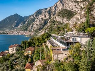 Villa Dirce hotel in Limone with modern terraced architecture nestled on hillside above Lake Garda, surrounded by dramatic limestone cliffs.
