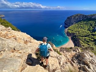Wanderer blickt auf die türkis-blaue Bucht von Coll de Baix
