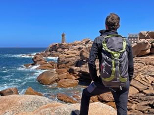 A hiker enjoys the view of the Phare de Ploumanac'h lighthouse