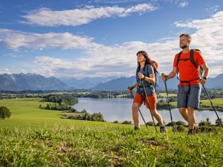 Hikers at Lake Riegsee with the mountain panorama in the background